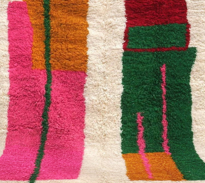 Close-up detail of the 'Safiya' Azilal rug, showing the texture of the wool, and the interplay of pink, orange, green and red color blocks.